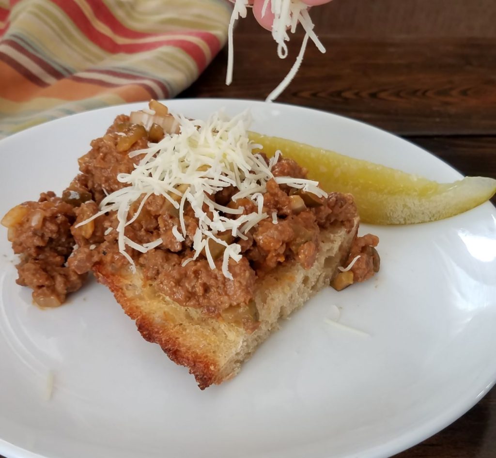 Spicy cheeseburger sloppy joe on slice of sourdough with pickle
