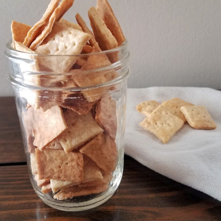 jar of sourdough crackers with a few cracker on a white napkin
