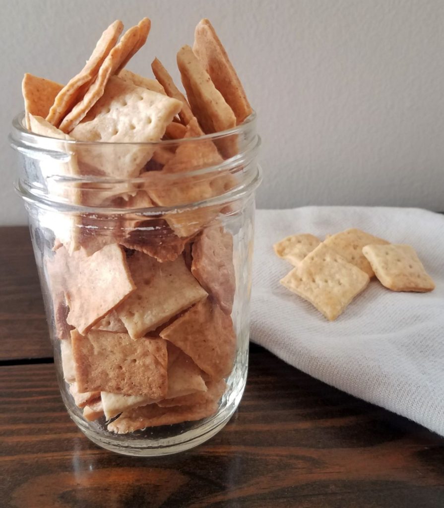 jar of sourdough crackers with a few cracker on a white napkin