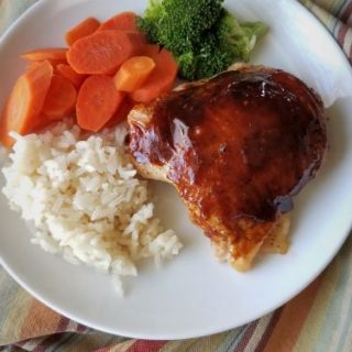 Asian chicken on plate with rice, carrots & broccoli sitting on stripped towel