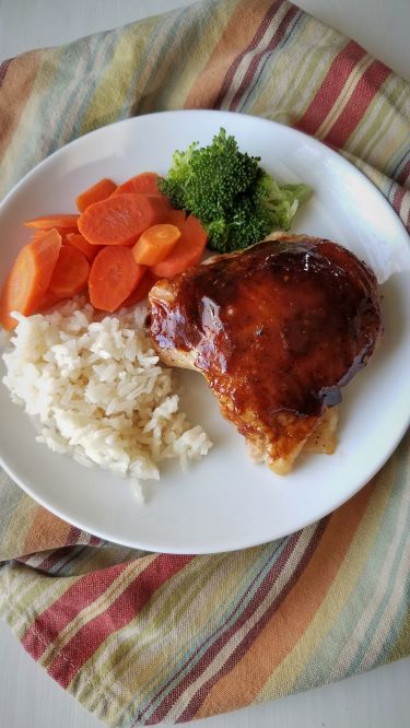 Asian chicken on plate with rice, carrots & broccoli sitting on stripped towel
