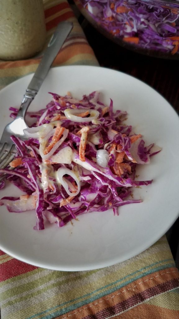 creamy coleslaw on plate with fork on striped towel