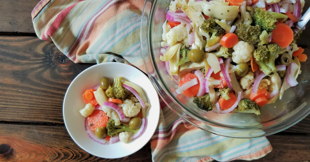Two bowls of marinated vegetable salad with striped towel