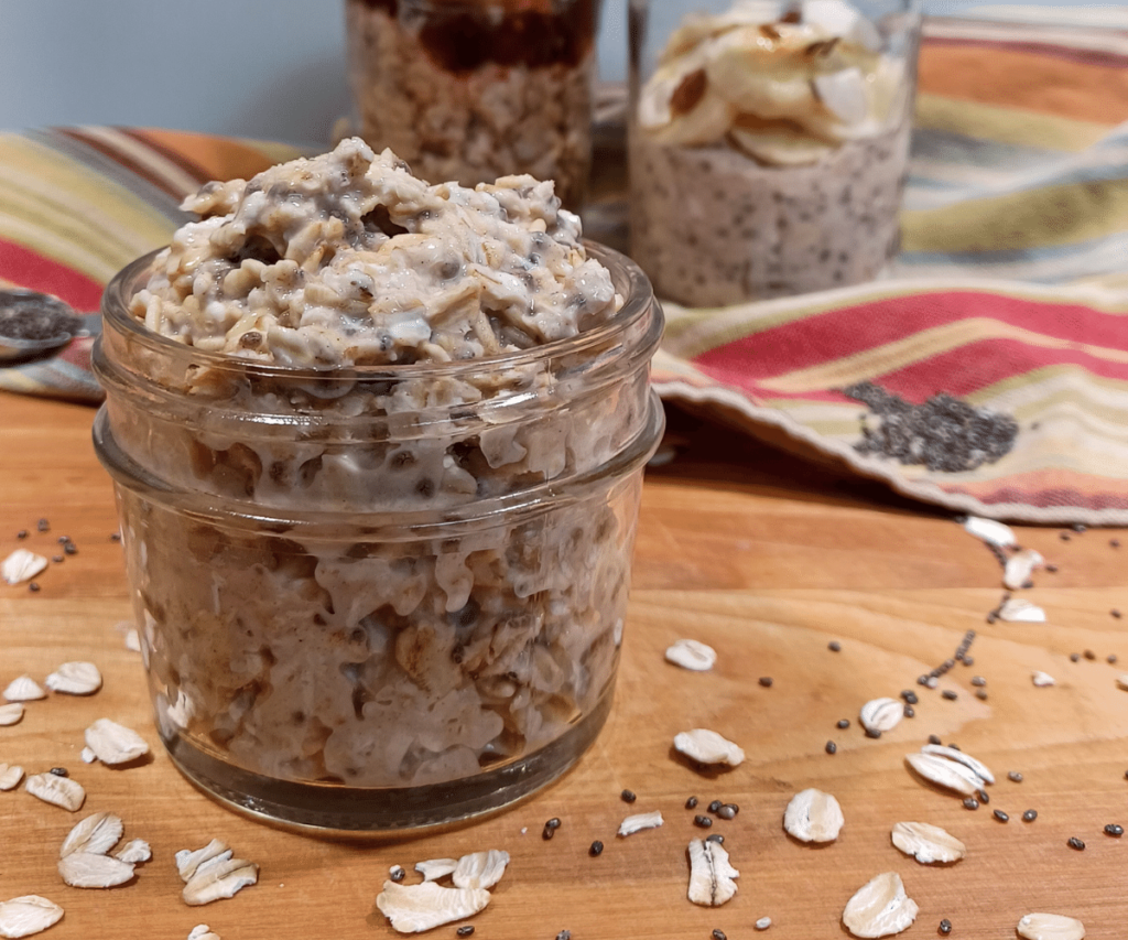 Easy overnight oats in mason jar with no toppings in front and 2 jars with toppings in background on stripped towel