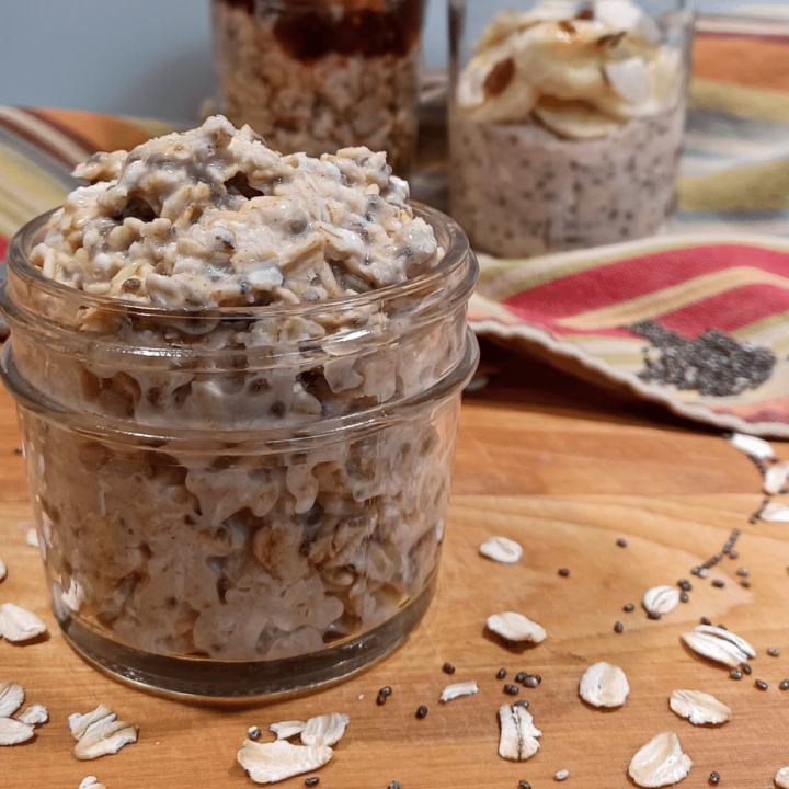 Easy overnight oats in mason jar with no toppings in front and 2 jars with toppings in background on stripped towel