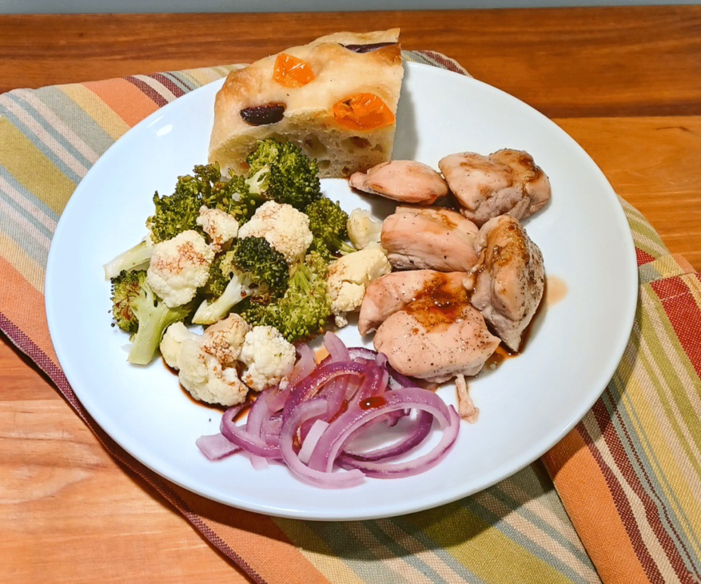 Sheet pan chicken on white plate ontop of towel with strips