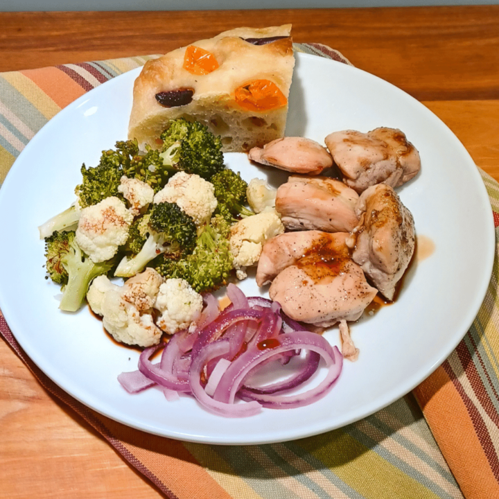 Sheet pan chicken on white plate ontop of towel with strips