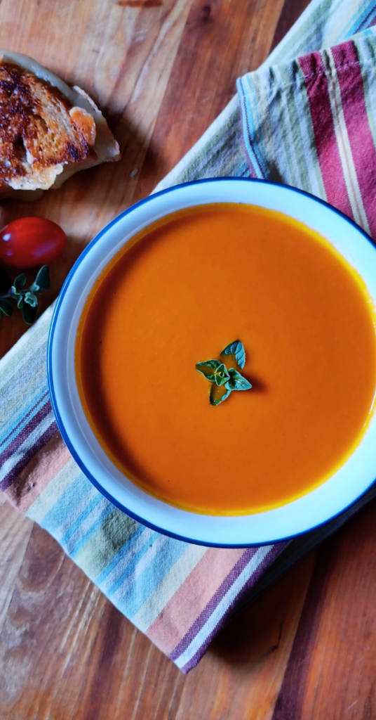 Homemade tomato soup in bowl sitting on stripped towel