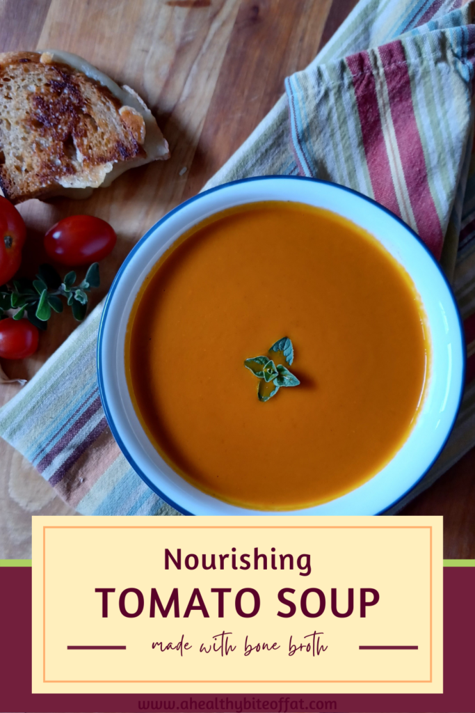 homemade tomato soup in bowl with grilled cheese in background