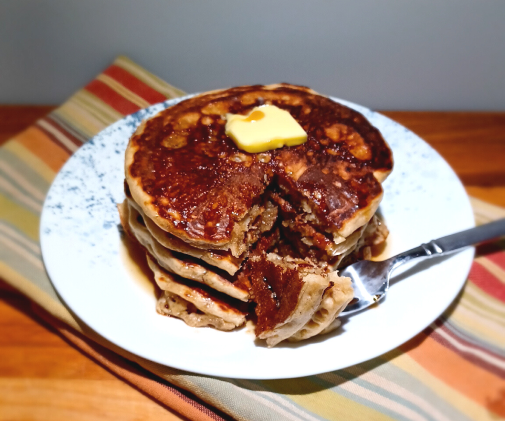 stack of sourdough pancakes with some on a fork laying on the plate