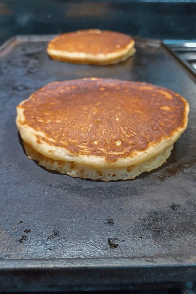 Sourdough pancakes cooking on cast iron griddle