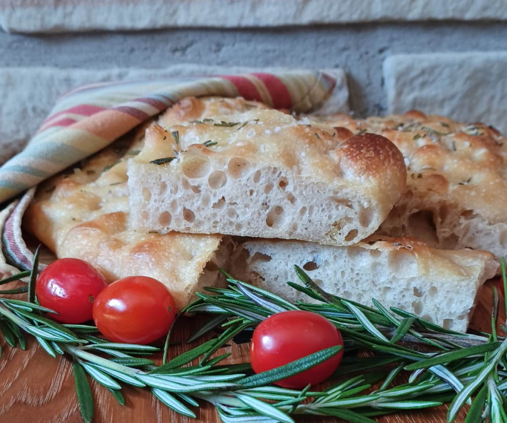 Sourdough focaccia in stack with cherry tomatoes and rosemary around it