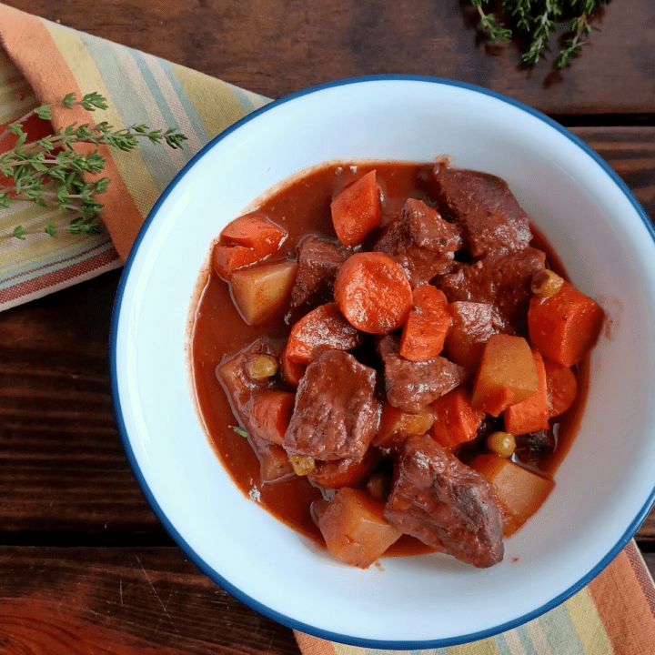 Homemade beef stew in white bowl with blue rim