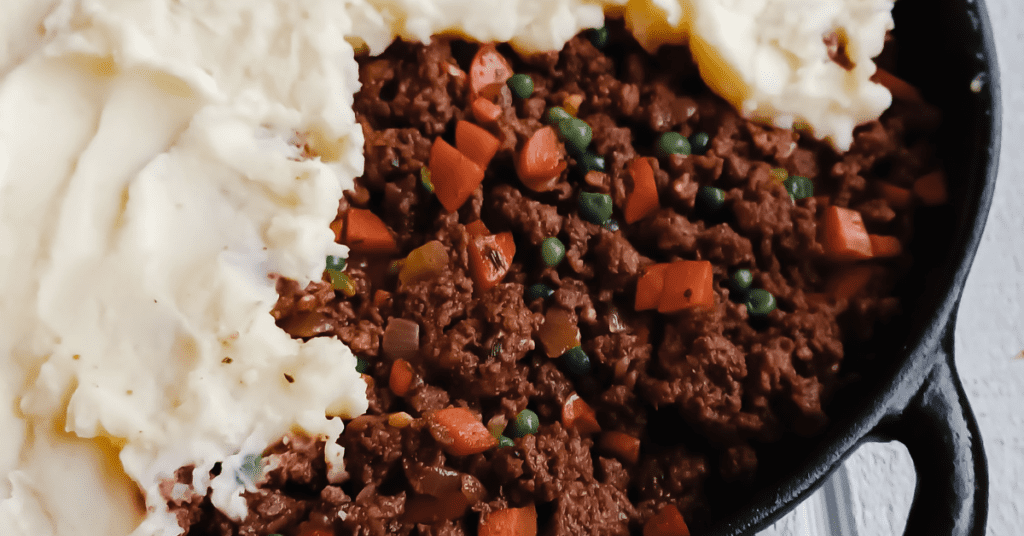 Cottage pie topped with mashed potatoes in cast iron skillet.