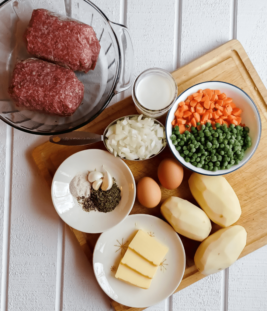 ingredeints for cottage pie on cutting board and in various size and colored bowls 