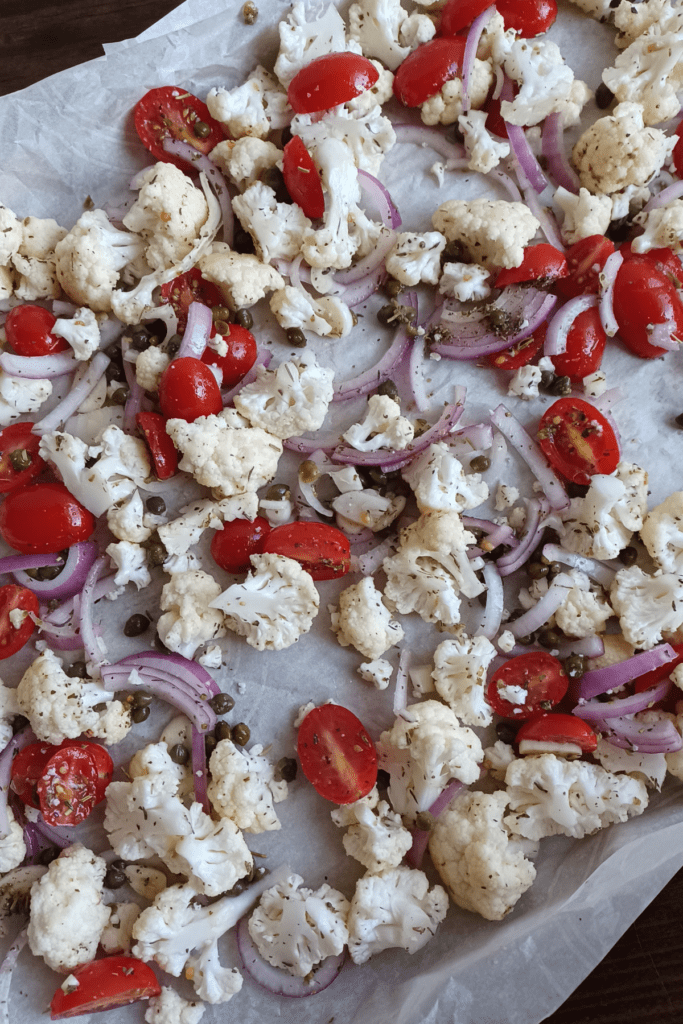 raw ingredients for roasted cauliflower on parchment paper lined sheet pan