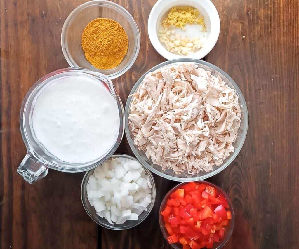 bowls of shredded chicken, red bell pepper, onion, coconut milk, curry powder, garlic and ginger.