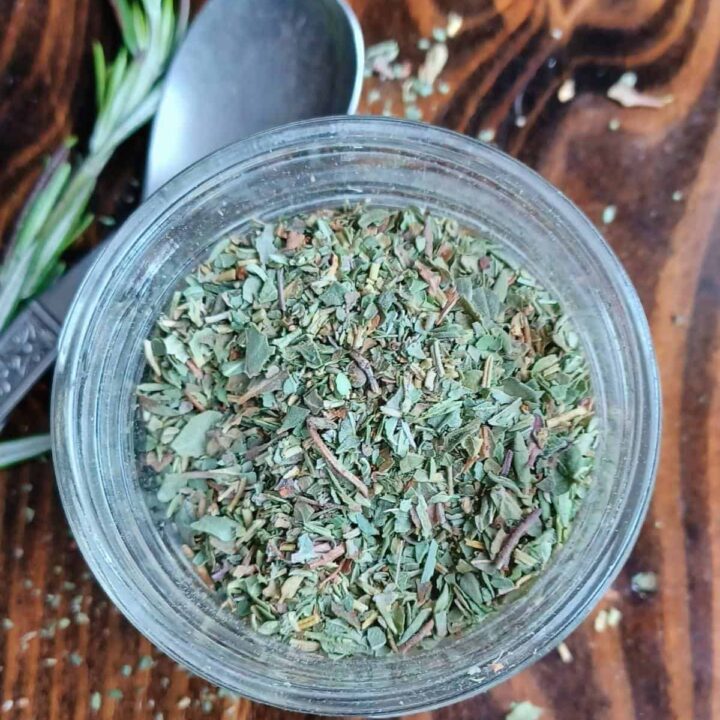 Italian herb blend in mason jar with spoon and rosemary springs