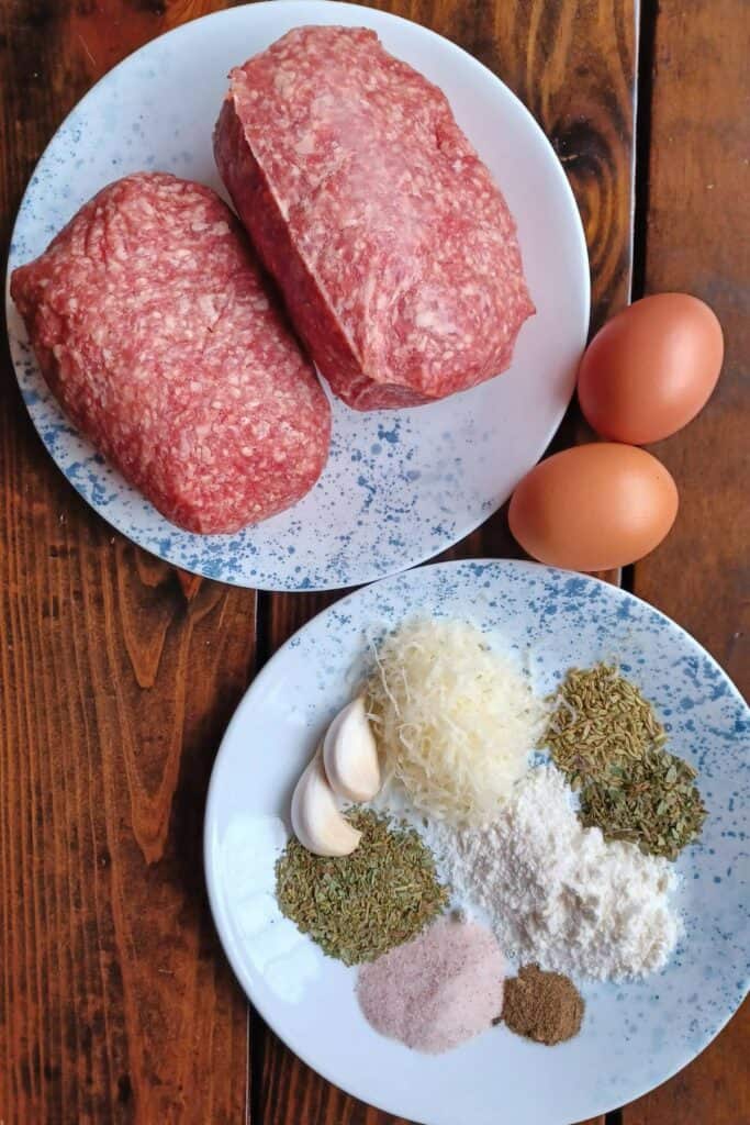 Ingredients for homemade meatballs on two white plates with blue speckles