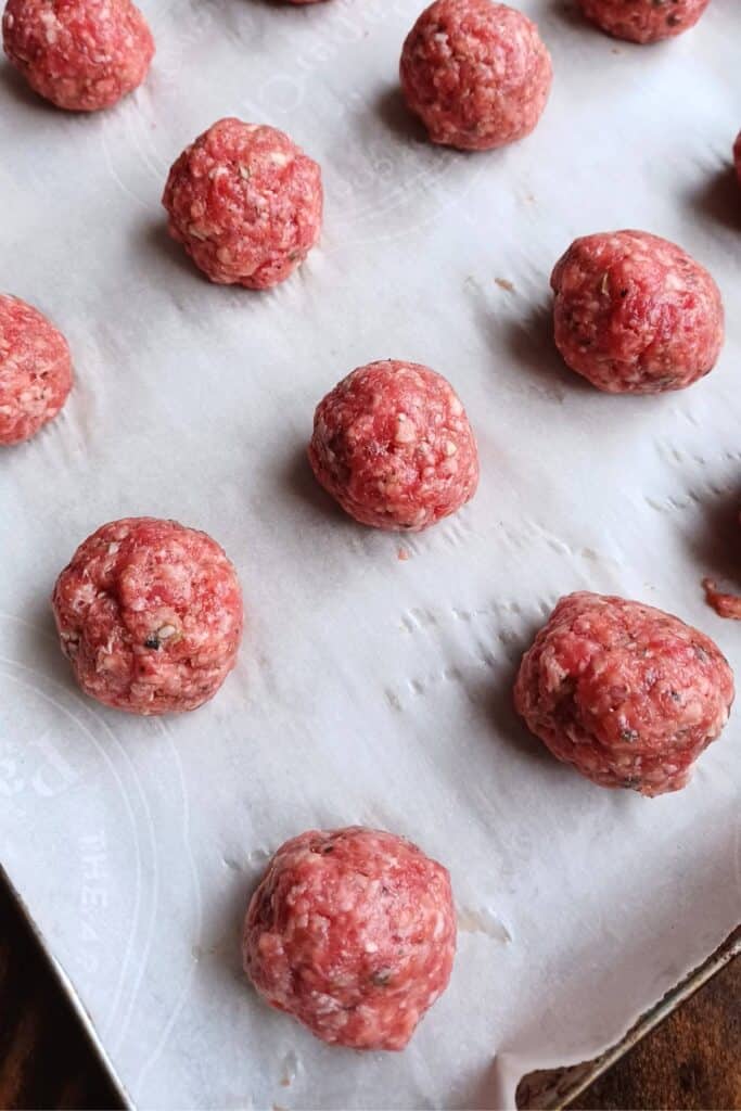 homemade meatballs rolled and place on a baking sheet lined with parchment paper