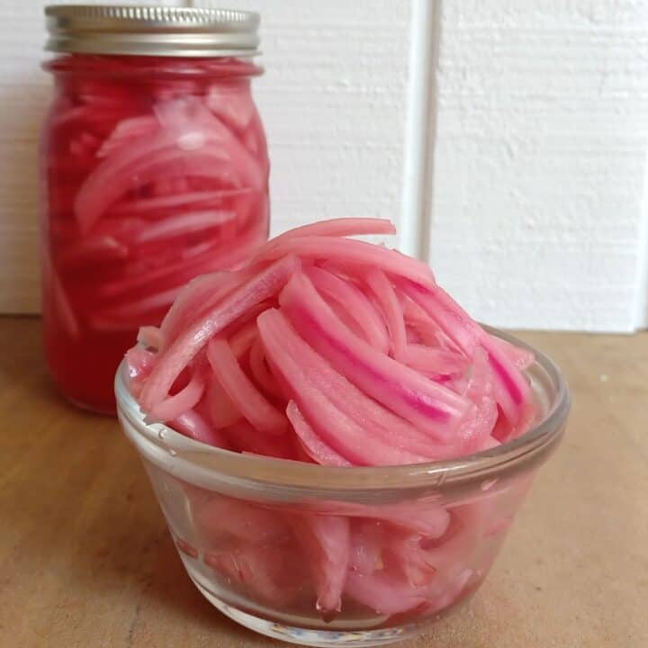 Pickled red onions in a small glass bowl and in a mason jar