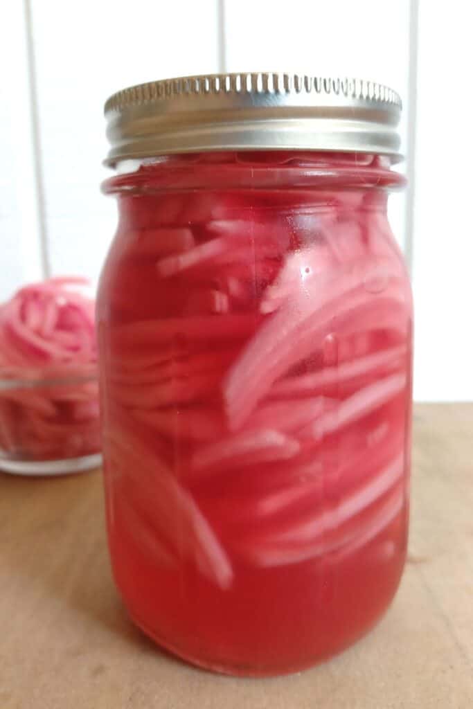 mason jar and small glass bowl filled with easy pickled red onions.