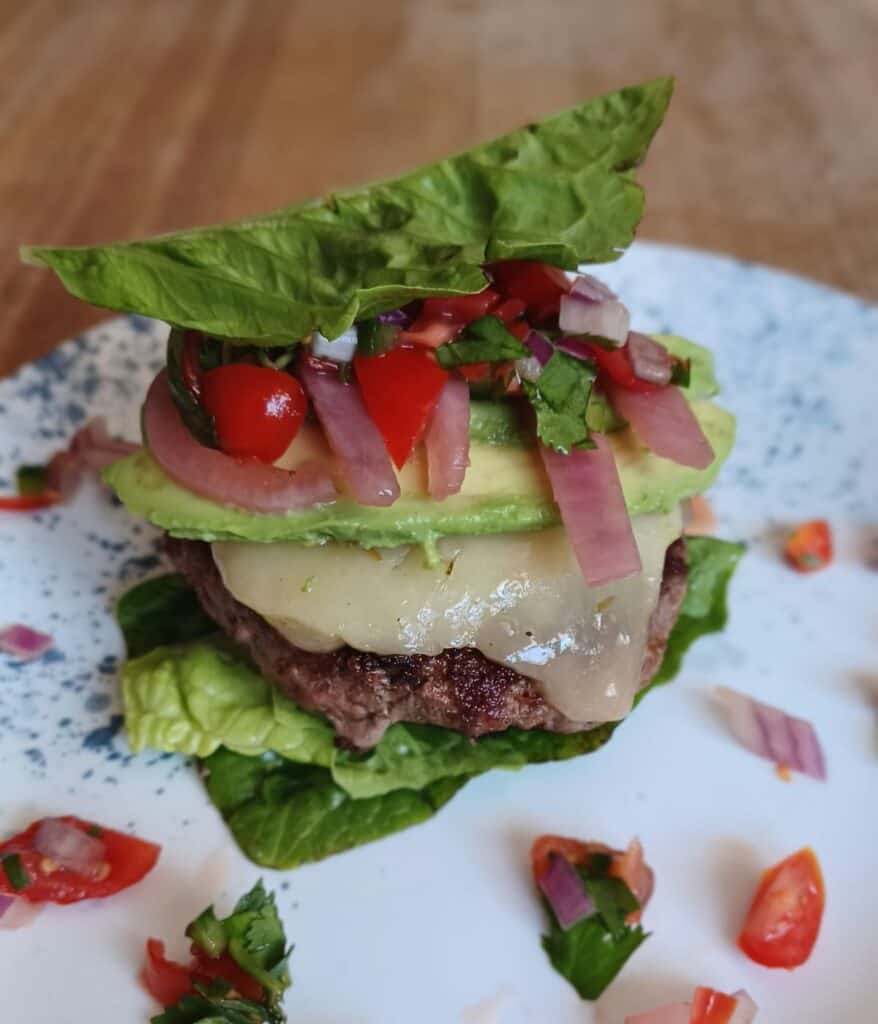 Salsa burger in lettuce wrap on a white plate with blue dots.  